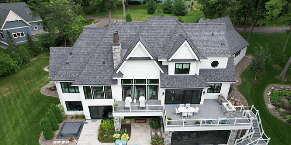 Image of a gray composite roof on top of a two story home in a green field